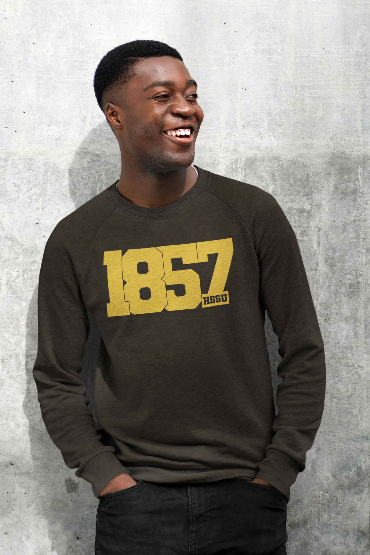 young black man smiling in a leaned pose wearing brown sweatshirt that reads 1857 HSSU.