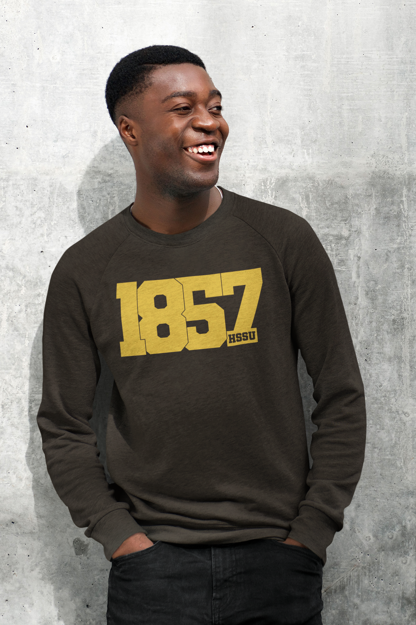 young black man smiling in a leaned pose wearing brown sweatshirt that reads 1857 HSSU. 